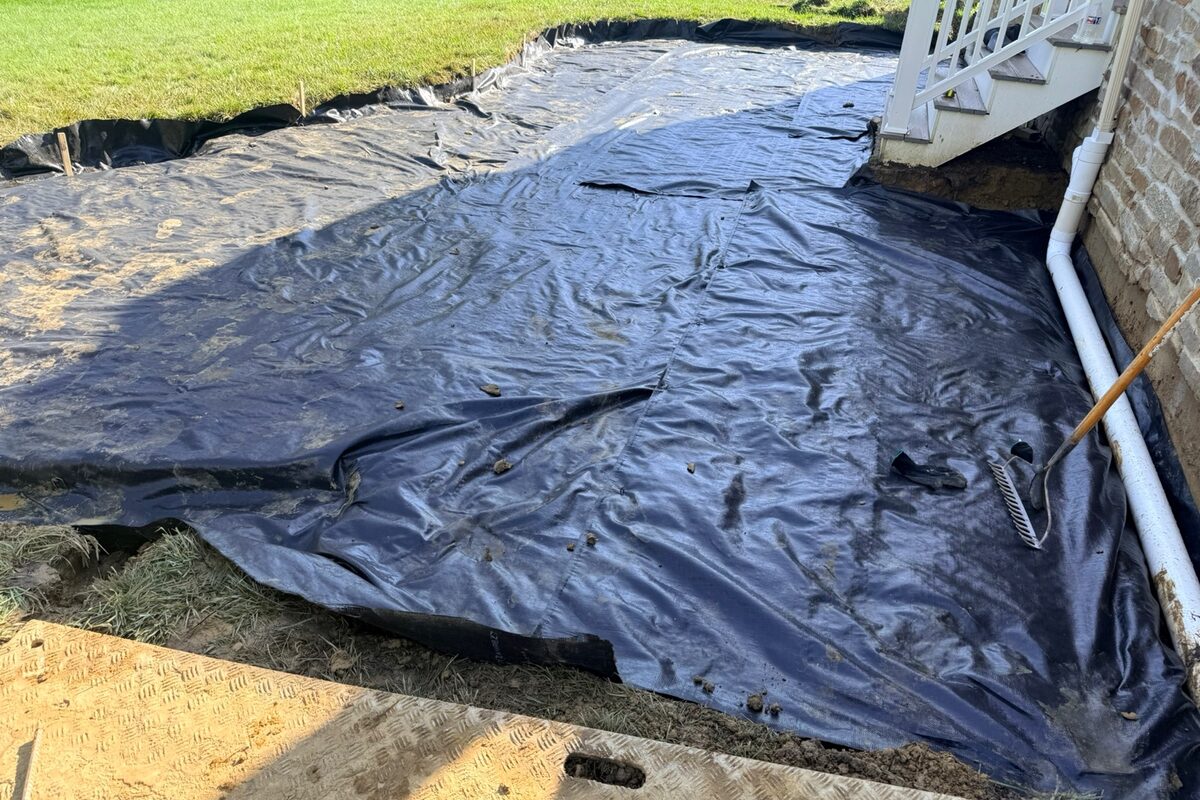 Geotextile fabric installed across a patio excavation before the gravel base