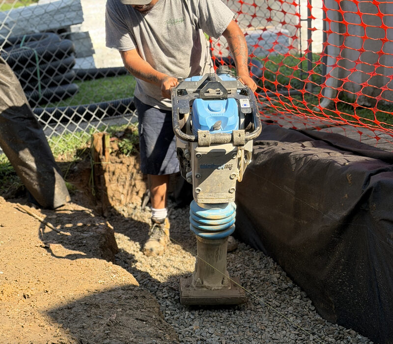 Arborvine crew compacting the gravel base behind a retaining wall